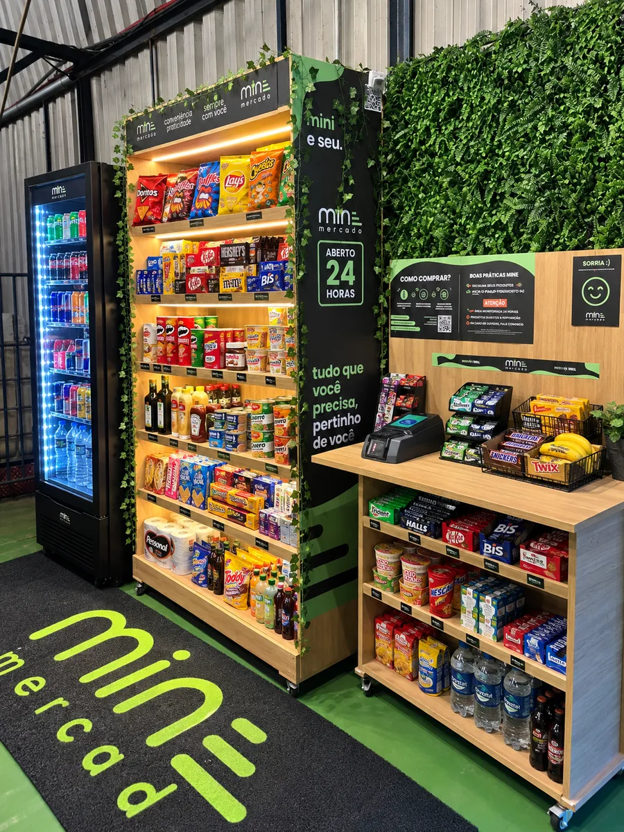 Unidade do MINE Mercado em uma empresa, com geladeira de bebidas e estante de produtos